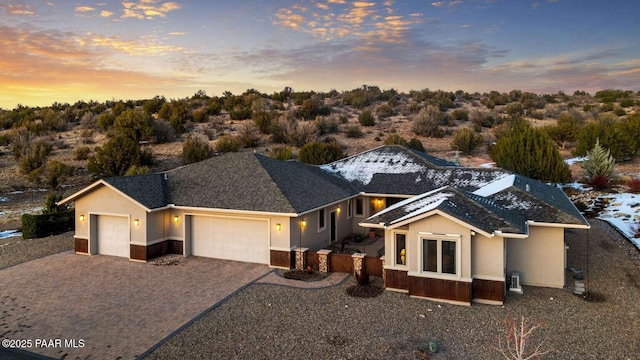 view of front of property with stucco siding, decorative driveway, a garage, and fence