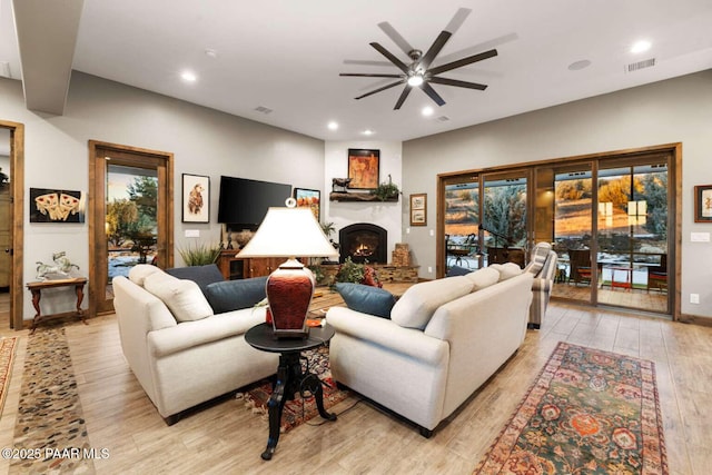 living area featuring light wood-type flooring, visible vents, a large fireplace, and recessed lighting