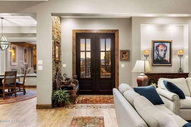 foyer featuring light wood-style flooring, french doors, and an inviting chandelier