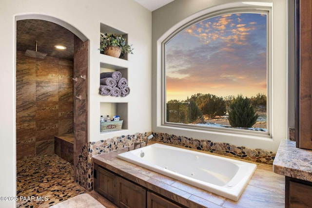 bathroom featuring tiled shower and a tub with jets