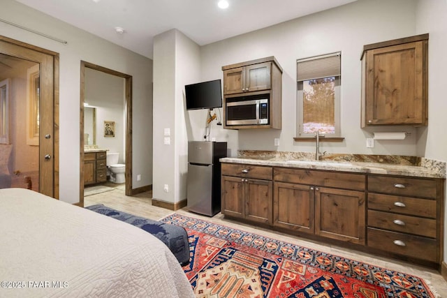 bedroom featuring a sink, baseboards, and freestanding refrigerator