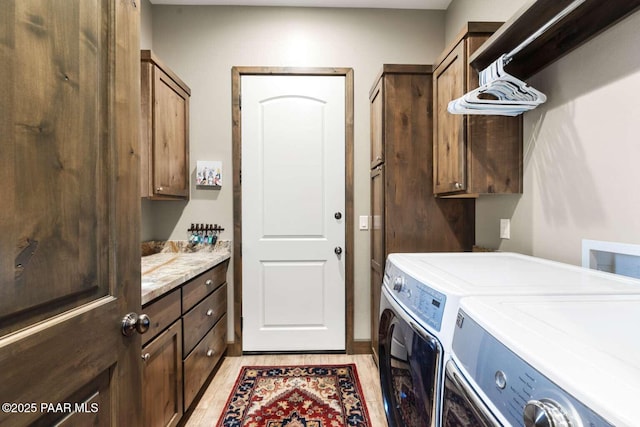 laundry area with washer and dryer, light wood-type flooring, and cabinet space