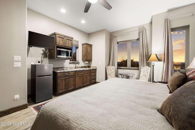 bedroom with baseboards, light wood finished floors, recessed lighting, freestanding refrigerator, and a sink