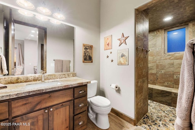 bathroom with vanity, wood finished floors, baseboards, a walk in shower, and toilet