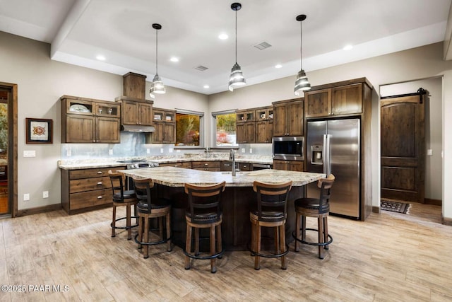 kitchen featuring stainless steel appliances, a barn door, a spacious island, and a breakfast bar