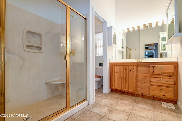 bathroom featuring tile patterned flooring, a shower with door, vanity, and toilet