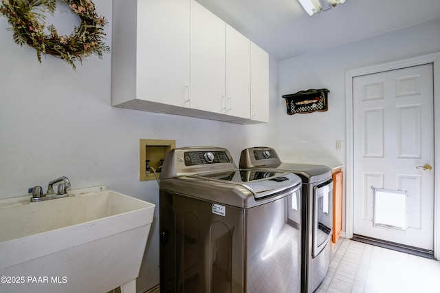 clothes washing area with cabinets, washing machine and dryer, and sink