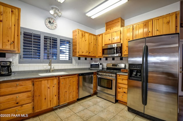 kitchen featuring decorative backsplash, sink, light tile patterned floors, and stainless steel appliances