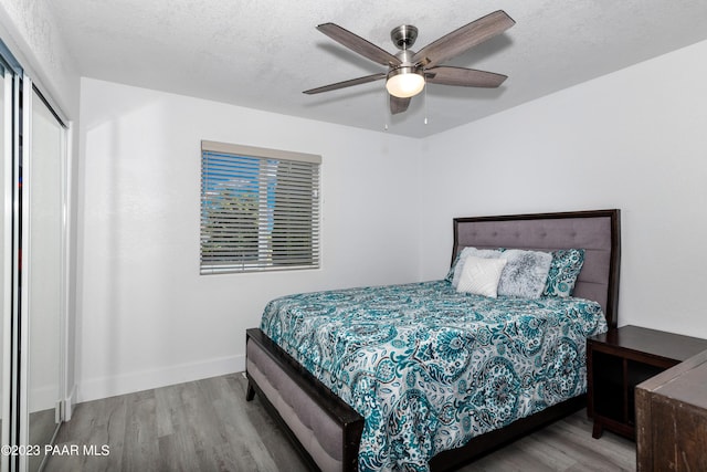 bedroom with a closet, ceiling fan, hardwood / wood-style floors, and a textured ceiling