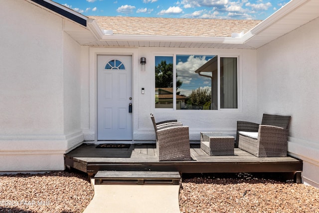 view of exterior entry featuring an outdoor living space and a deck