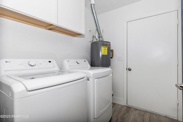 clothes washing area featuring cabinets, wood-type flooring, washer and clothes dryer, and water heater