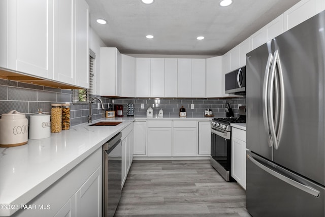 kitchen featuring decorative backsplash, sink, white cabinets, and appliances with stainless steel finishes