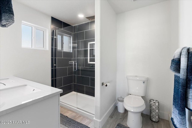 bathroom featuring wood-type flooring, vanity, toilet, and a shower with door