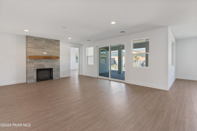 unfurnished living room featuring hardwood / wood-style floors and a tile fireplace