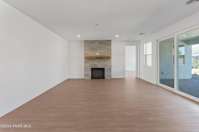 unfurnished living room featuring light hardwood / wood-style floors and a tiled fireplace