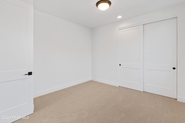 unfurnished bedroom with light carpet and a closet