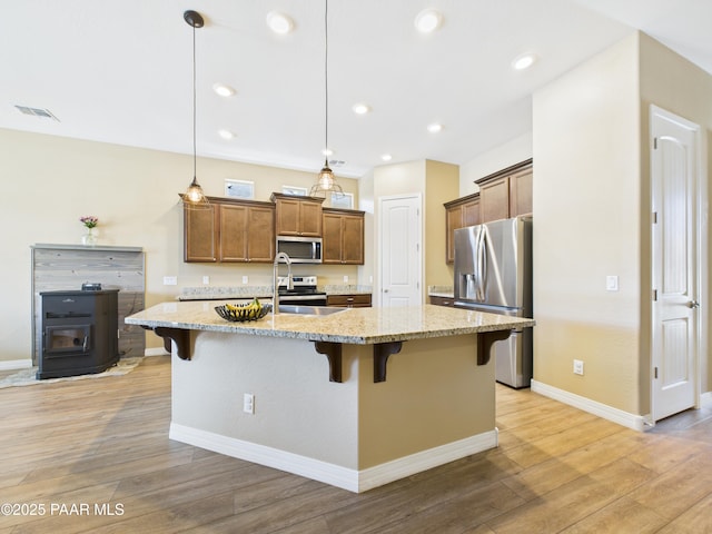 kitchen featuring light wood finished floors, appliances with stainless steel finishes, a breakfast bar area, and a sink
