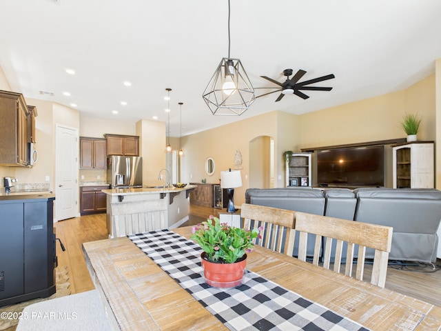 dining room featuring arched walkways, light wood-style flooring, a ceiling fan, and recessed lighting