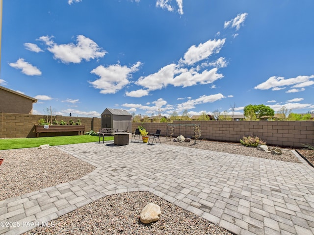 view of patio featuring an outdoor structure, a shed, a fenced backyard, and an outdoor fire pit