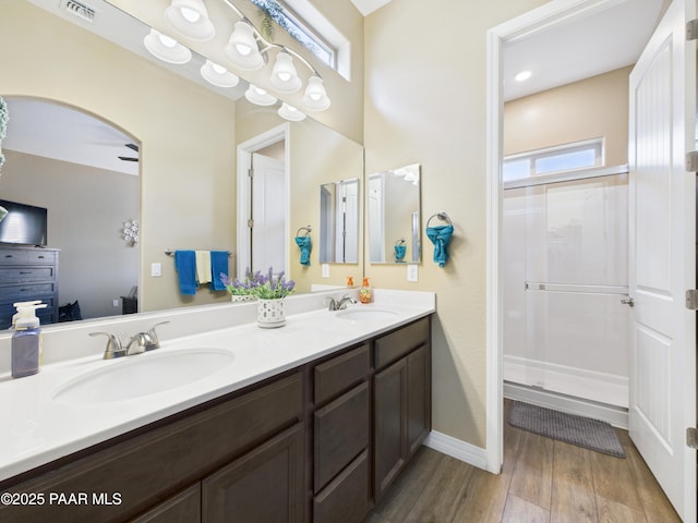 bathroom featuring wood finished floors, a sink, visible vents, and double vanity