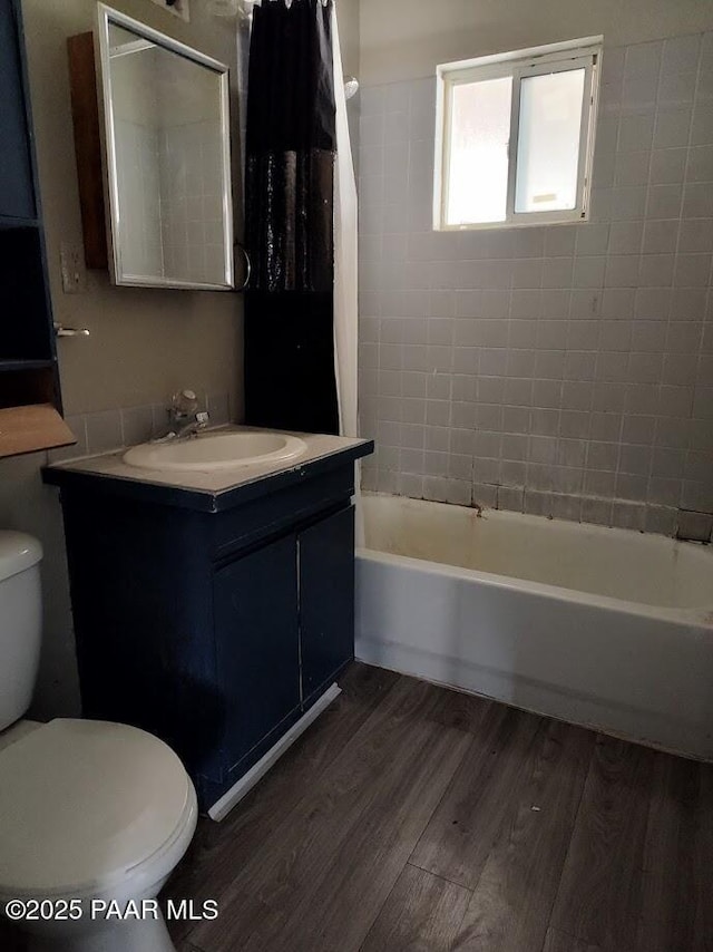 full bathroom with hardwood / wood-style flooring, toilet, vanity, and tiled shower / bath