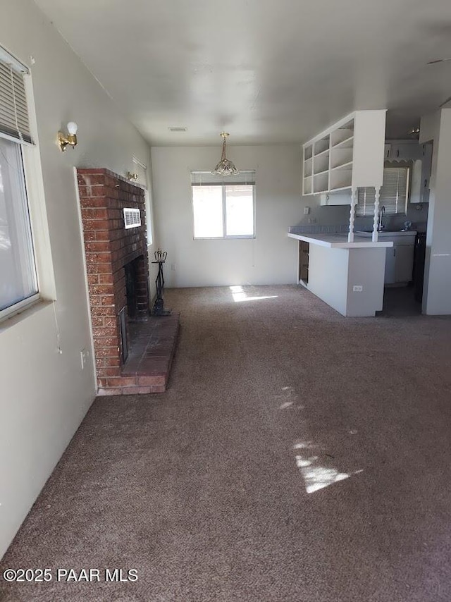 unfurnished living room featuring a brick fireplace and dark carpet