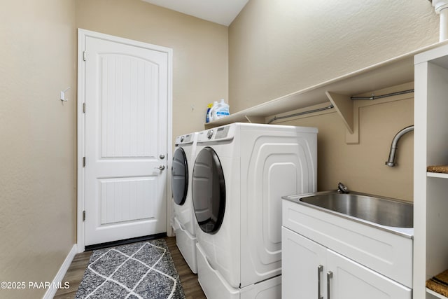 laundry area featuring cabinets, washer and dryer, dark hardwood / wood-style flooring, and sink