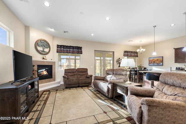 living room featuring a chandelier, light hardwood / wood-style flooring, and a tiled fireplace