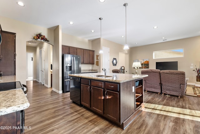 kitchen featuring stainless steel fridge, dark brown cabinetry, sink, black dishwasher, and an island with sink