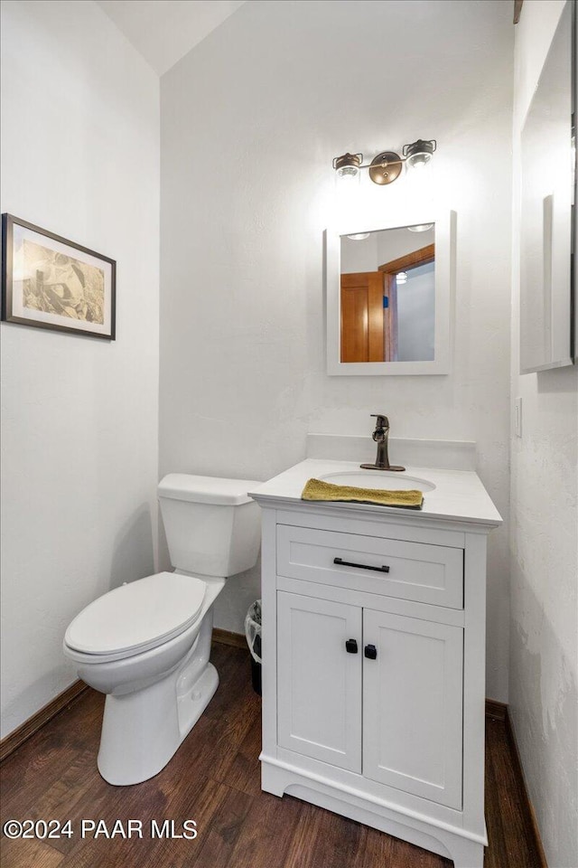 bathroom with wood-type flooring, vanity, and toilet