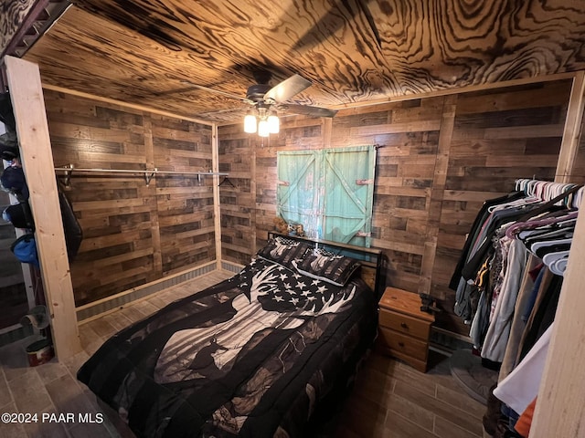 bedroom with wood walls, ceiling fan, wood ceiling, and dark hardwood / wood-style floors