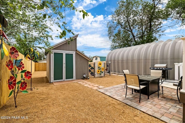 exterior space with a fenced backyard, outdoor dining area, an outbuilding, and a patio