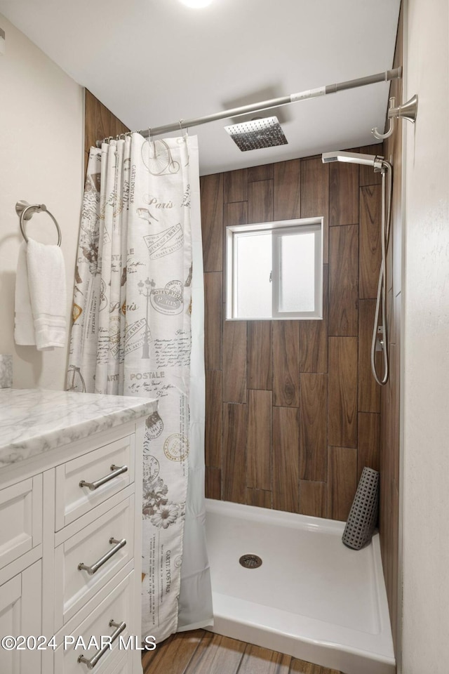 full bathroom featuring tiled shower and vanity