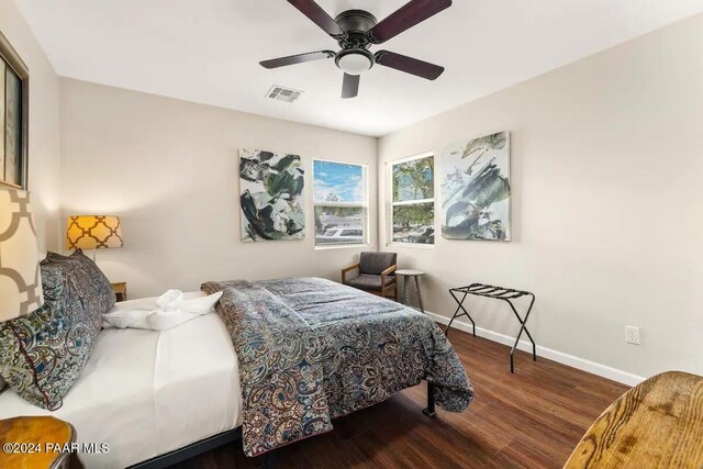 bedroom featuring a ceiling fan, wood finished floors, visible vents, and baseboards