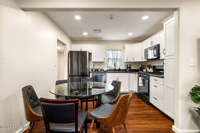 kitchen with dark wood-type flooring, dark countertops, visible vents, and appliances with stainless steel finishes