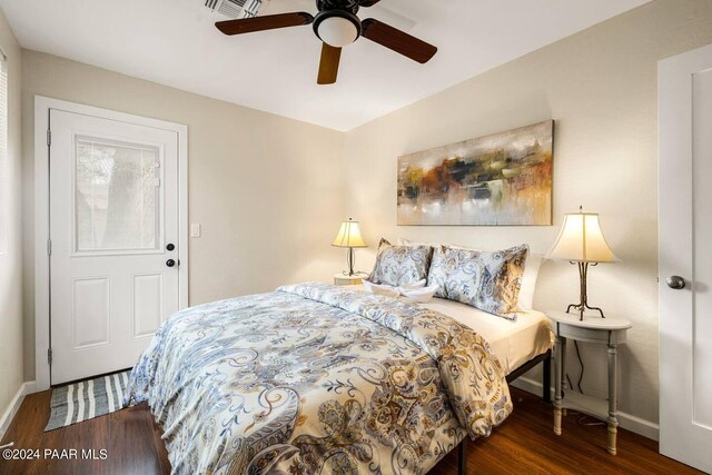 bedroom featuring a ceiling fan, wood finished floors, visible vents, and baseboards