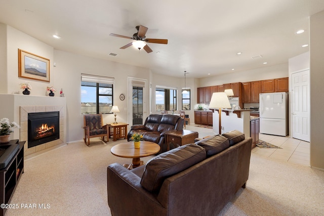 living room featuring a tiled fireplace, recessed lighting, visible vents, and light carpet