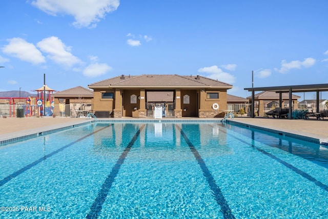 pool with playground community, a patio, and fence