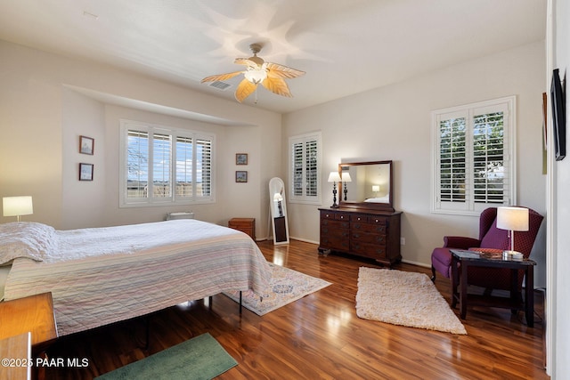 bedroom with visible vents, multiple windows, baseboards, and wood finished floors