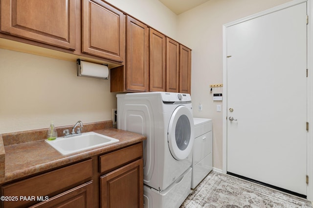 washroom featuring cabinet space, separate washer and dryer, and a sink