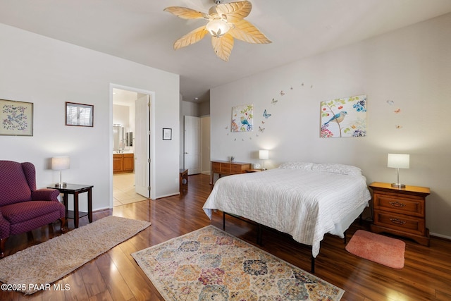 bedroom featuring baseboards, ensuite bathroom, ceiling fan, and wood finished floors