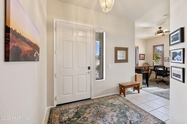 foyer featuring light tile patterned flooring, a ceiling fan, and baseboards