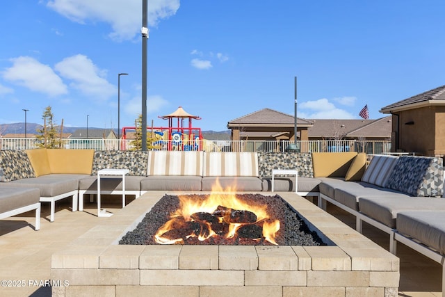 view of patio / terrace with an outdoor living space with a fire pit, fence, and playground community