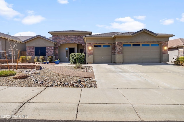 prairie-style home featuring a tiled roof, concrete driveway, stucco siding, stone siding, and an attached garage