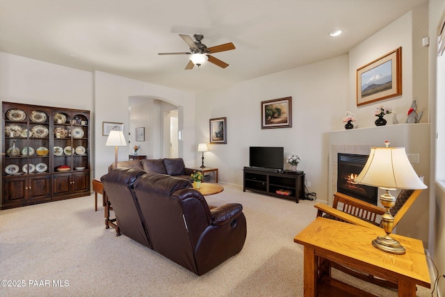 living room with a ceiling fan, recessed lighting, carpet floors, arched walkways, and a fireplace