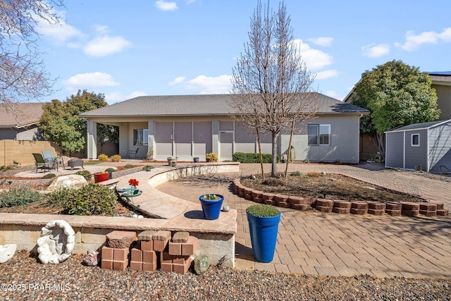 rear view of house featuring stucco siding, an outbuilding, a patio, fence, and a storage shed