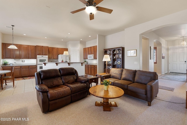 living room with a ceiling fan, recessed lighting, arched walkways, and light carpet