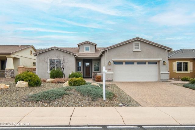 view of front of house with stucco siding, an attached garage, a tile roof, and decorative driveway