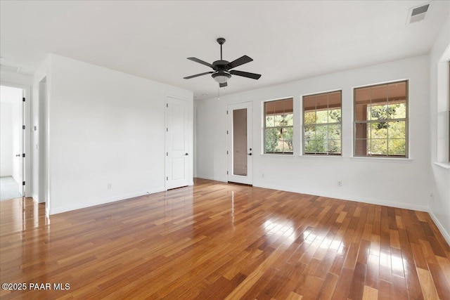 empty room with visible vents, baseboards, ceiling fan, and wood finished floors