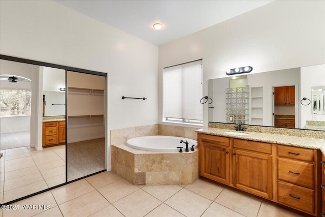 full bathroom with tile patterned floors, a spacious closet, vanity, and a garden tub